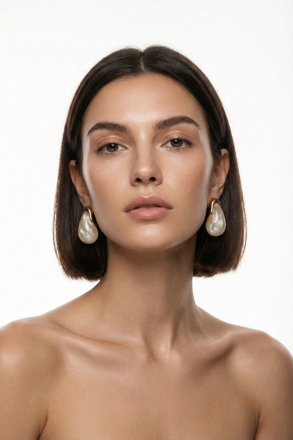 Boucles d’oreilles Vendôme dorées avec grande perle fantaisie écrue en forme de goutte, portées par une femme brune au carré sur fond blanc. Bijou élégant, minimaliste et raffiné.
