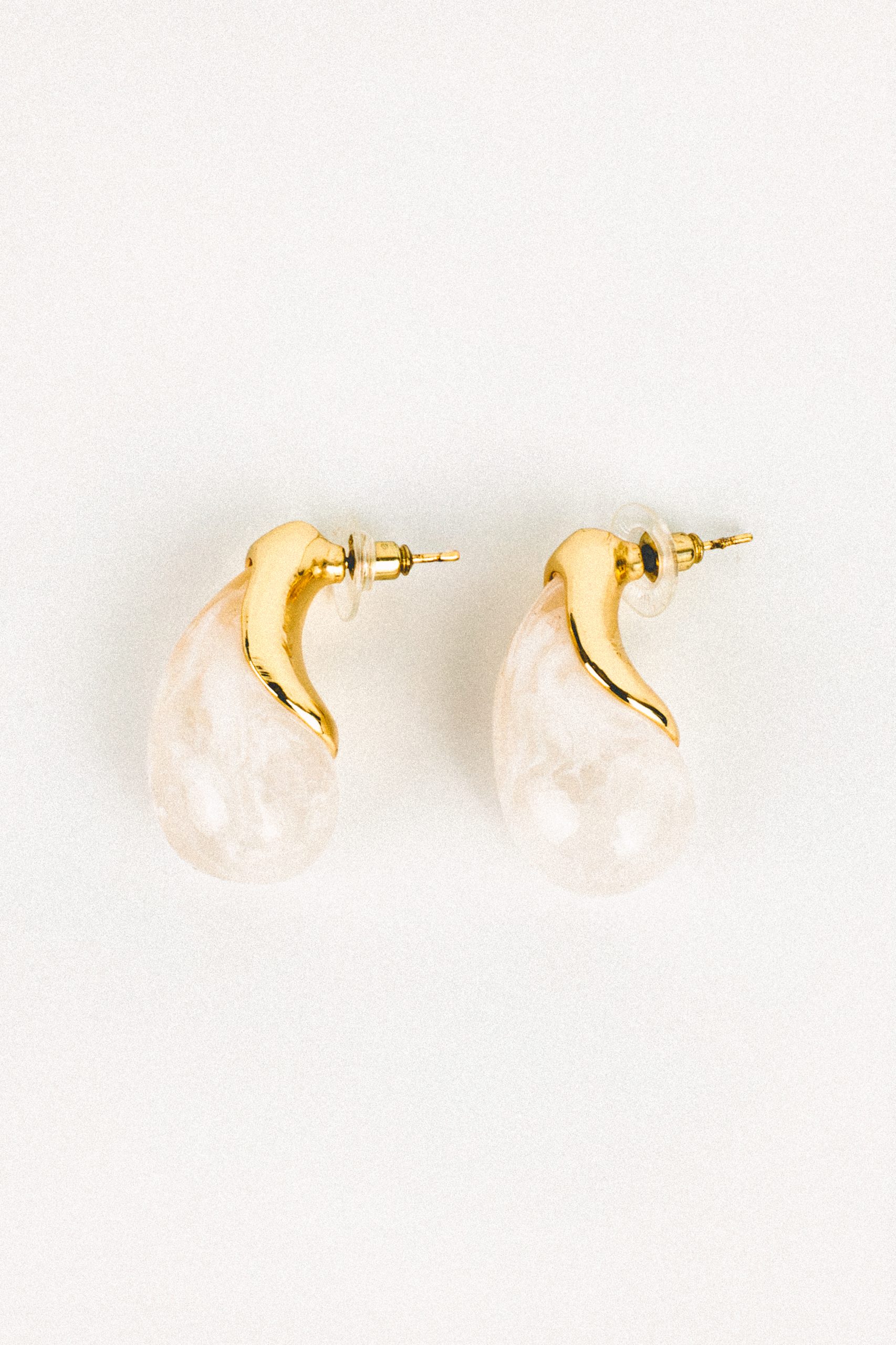 Boucles d’oreilles Vendôme dorées avec grande perle fantaisie écrue en forme de goutte, portées sur fond blanc. Bijou élégant, minimaliste et raffiné.