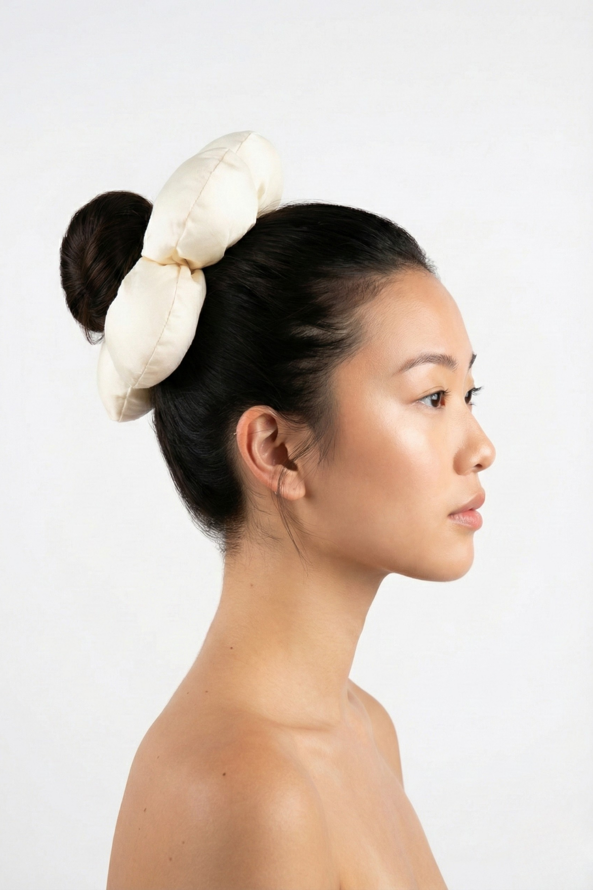 Chouchou 3D Saint-Germain en polyester écru, en forme de fleur XXL, porté sur un chignon haut. Accessoire de coiffure mariage élégant et volumineux.