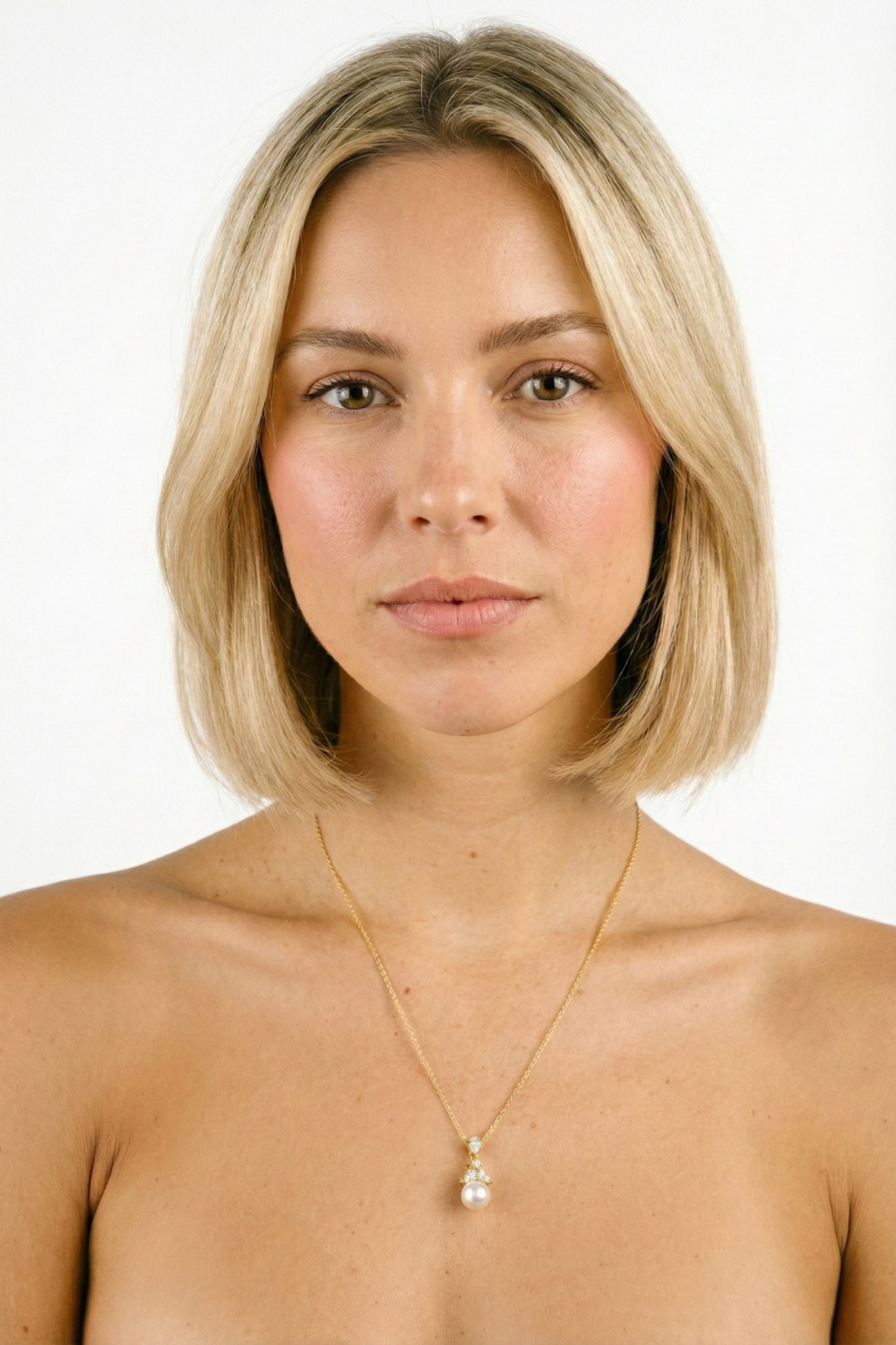 Collier Dauphine doré avec pendentif serti de strass brillants et perle fantaisie ronde, porté par une femme blonde au carré sur fond blanc. Bijou délicat et raffiné pour mariée.