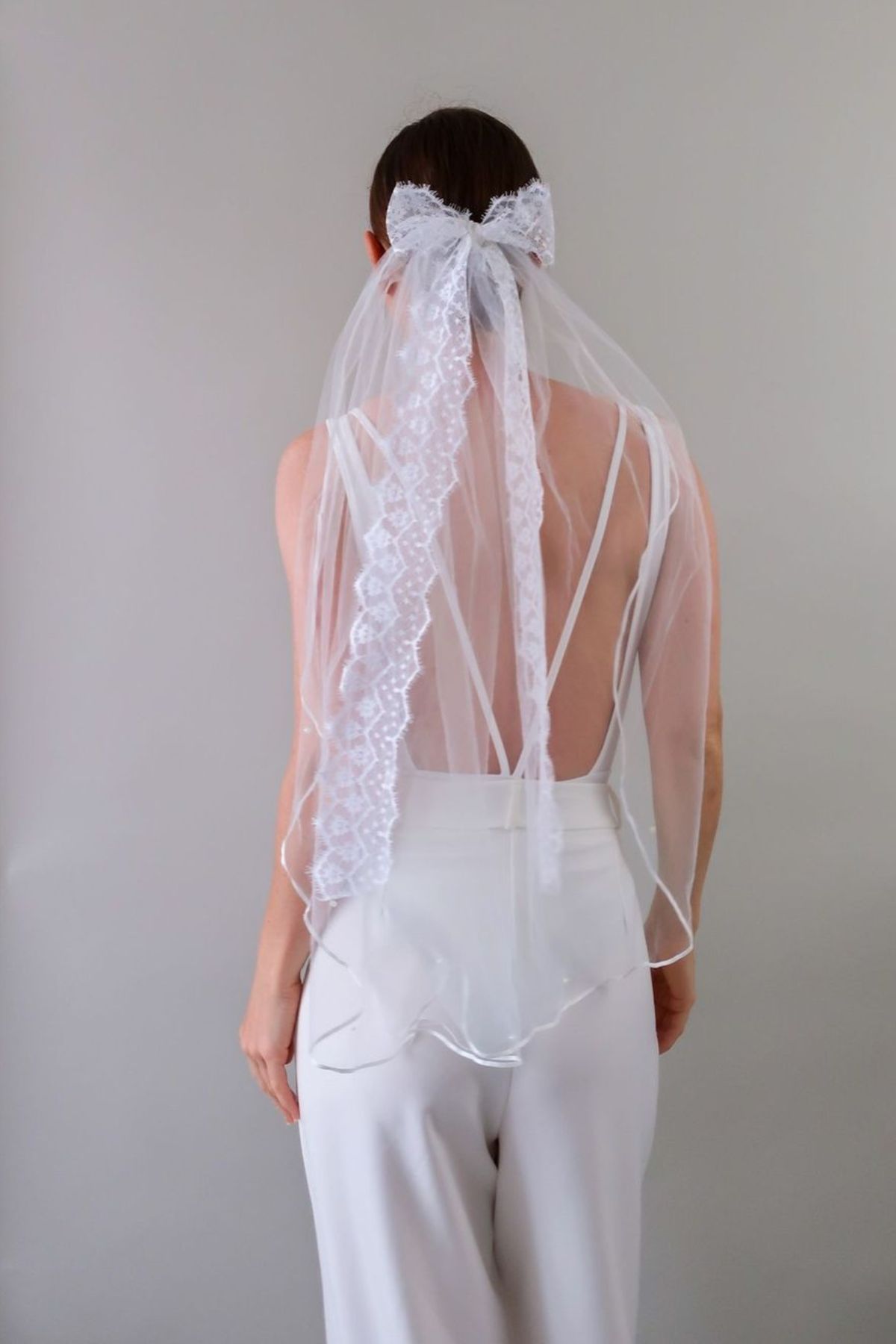 Mariée portant le voile Violaine mi-long en tulle léger avec nœud en dentelle vintage, style bohème rétro et élégant.